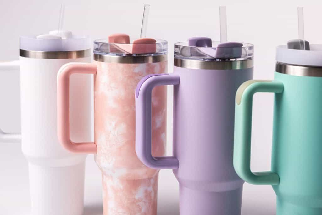 Colorful insulated tumblers with handles for beverages in pastel shades, perfect for summer drinks.